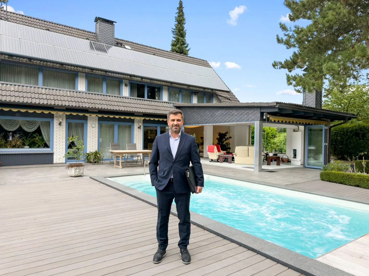 Murat Girtten vor einem Wohnhaus mit Terrasse und Pool